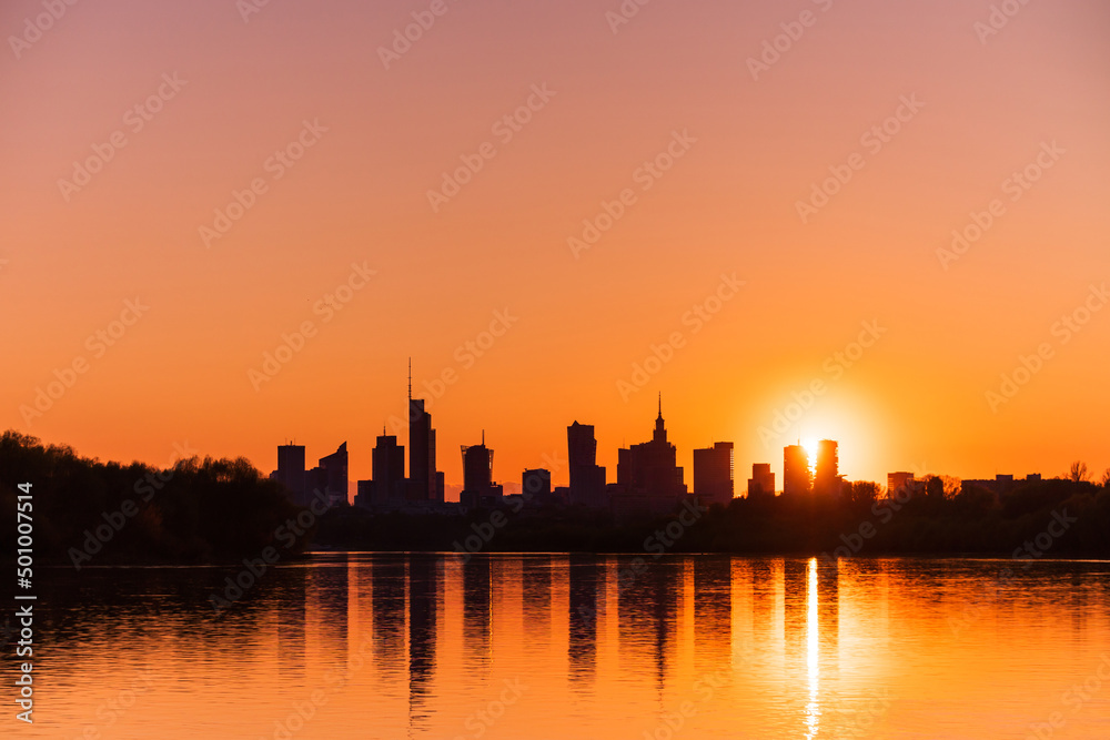 Big city skyline sunny evening in big city of Warsaw, Poland. High buildings skyscrapers on horizon over Wisla river surface. Sunset, downtown beautiful cityscape panorama lit with warm sun light