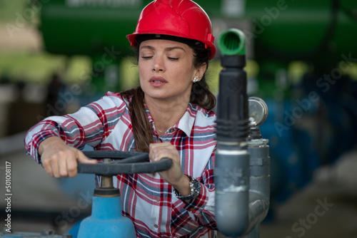 Female engineer turning valve on and off in outdoor plant