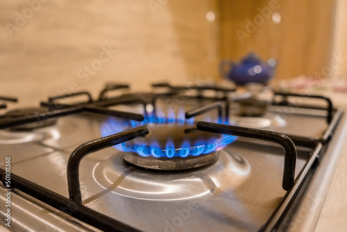 A burning match ignites the gas of the home gas stove in the kitchen