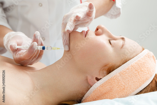 Cosmetologist performs the chin lift procedure by injecting beauty injections. Doctor injecting hyaluronic acid into the ching of a woman as a facial rejuvenation treatment.