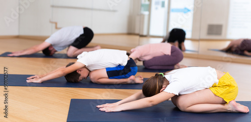 Teen girl and boy exercising with mother and father at yoga class, family practicing self-care