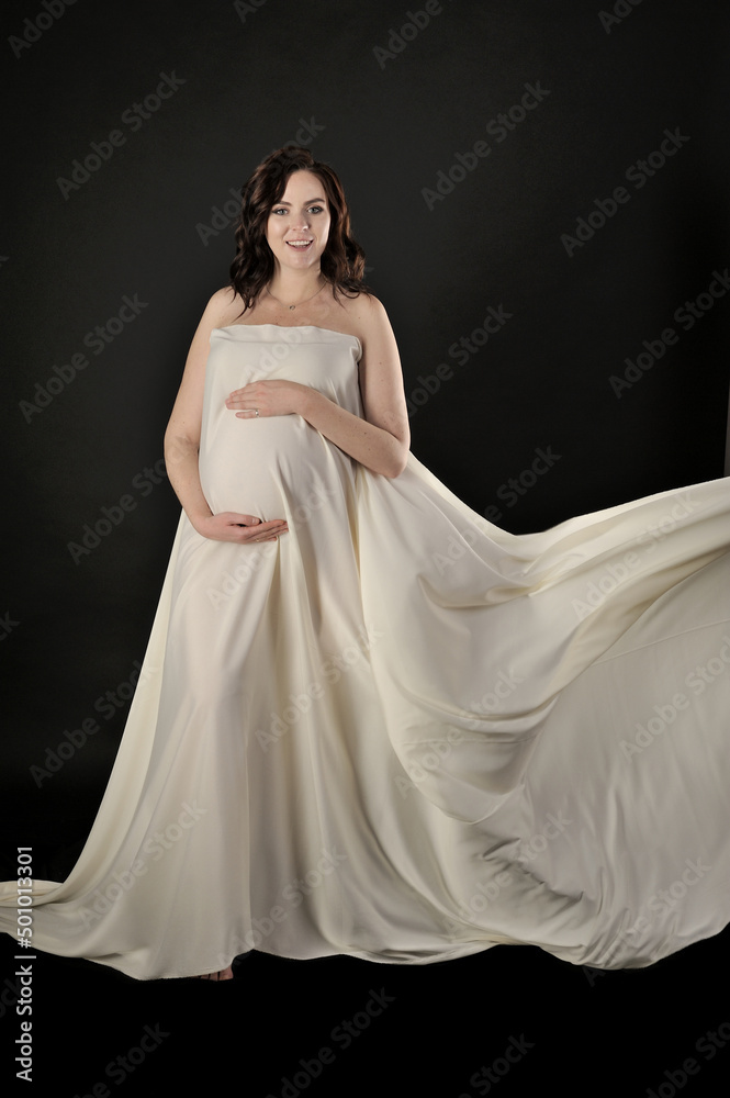 Fototapeta premium Beautiful pregnant woman in the dress posing isolated on the black