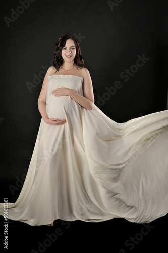 Beautiful pregnant woman in the dress posing isolated on the black