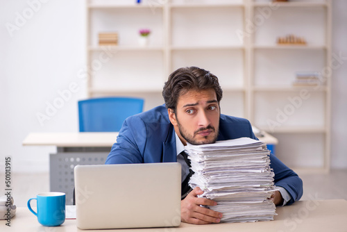 Young male employee and too much work in the office