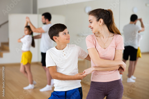 Young boy dancing with his mother during rehearsal in gym.