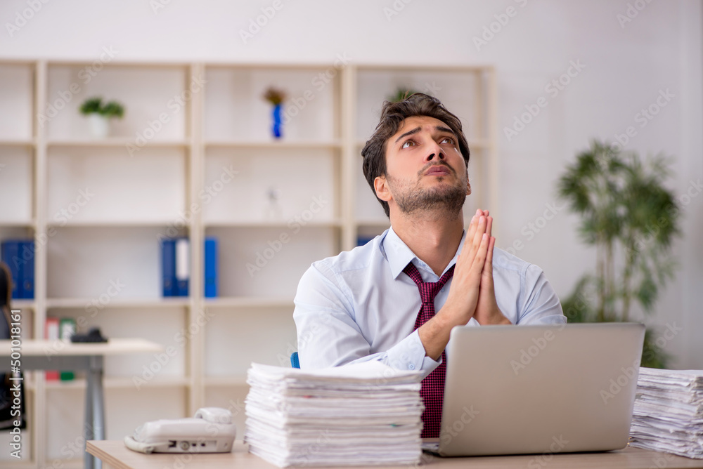 Young male employee and too much work in the office Young male employee and too much work in the office