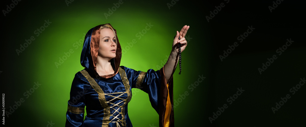 Soothsayer in a traditional dress with a rosary in her hands portrait on a dark background with copy space, hard light