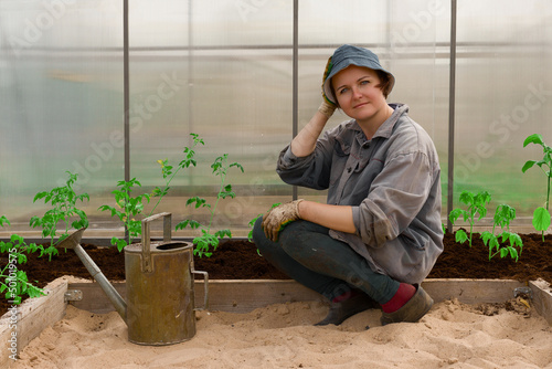 a farmer works in a greenhouse in spring, planting seedlings and watering