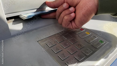 Unrecognizable man taking money out of the ATM