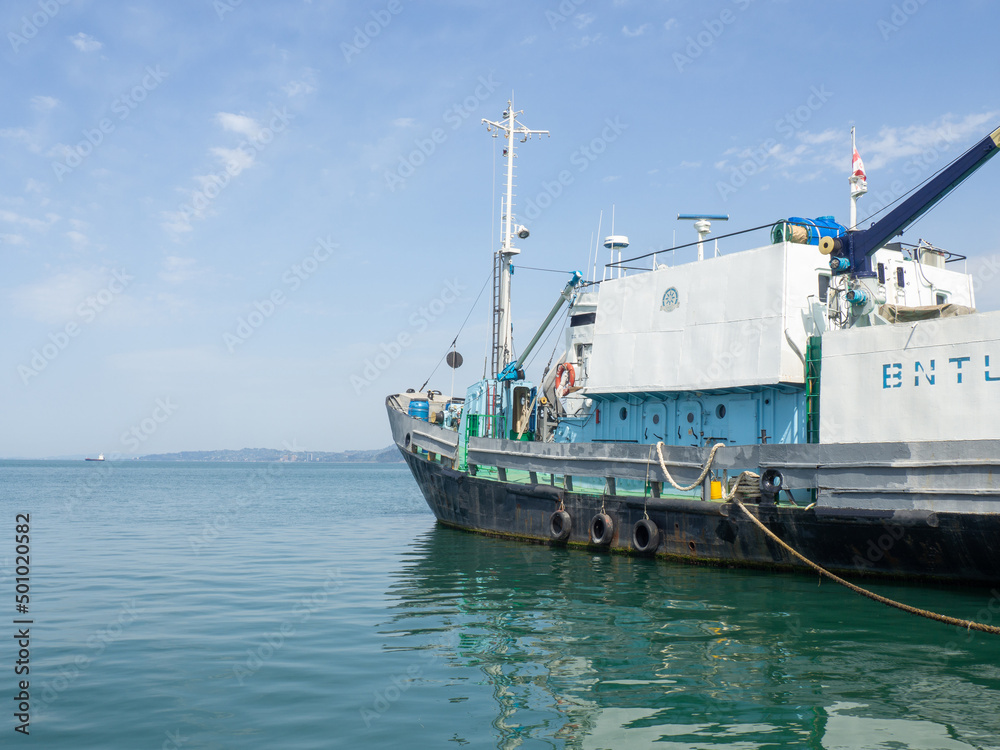 Protection of the side of the ship with car tires. Moored ship. Portholes in the hold. Ship at the pier. Equipment in the port. Protection of the side of the ship with car tires. Moored ship. Portholes in the hold. Ship at the pier. Equipment in the port.