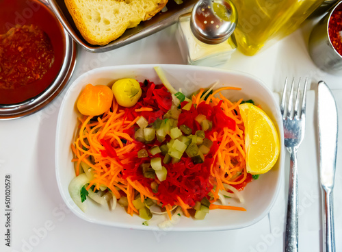 Delicious vegetable salad with carrot, tomato, pickles and slice of lemon on white plate