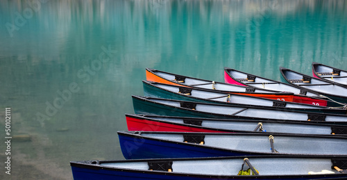 Colorful canoe lined up on turqoise blue lake