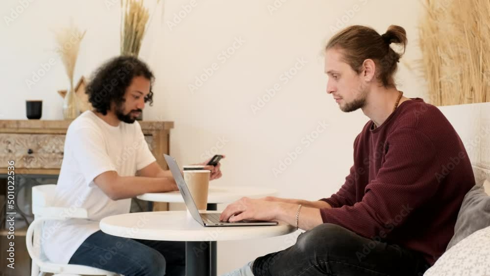 Two Young Freelancers Work and Use Computers and Laptops, Create A New Business Project, Are in a Bright Cafe, drink Coffee and Tea Two Young Freelancers Work and Use Computers and Laptops, Create A New Business Project, Are in a Bright Cafe, drink Coffee and Tea