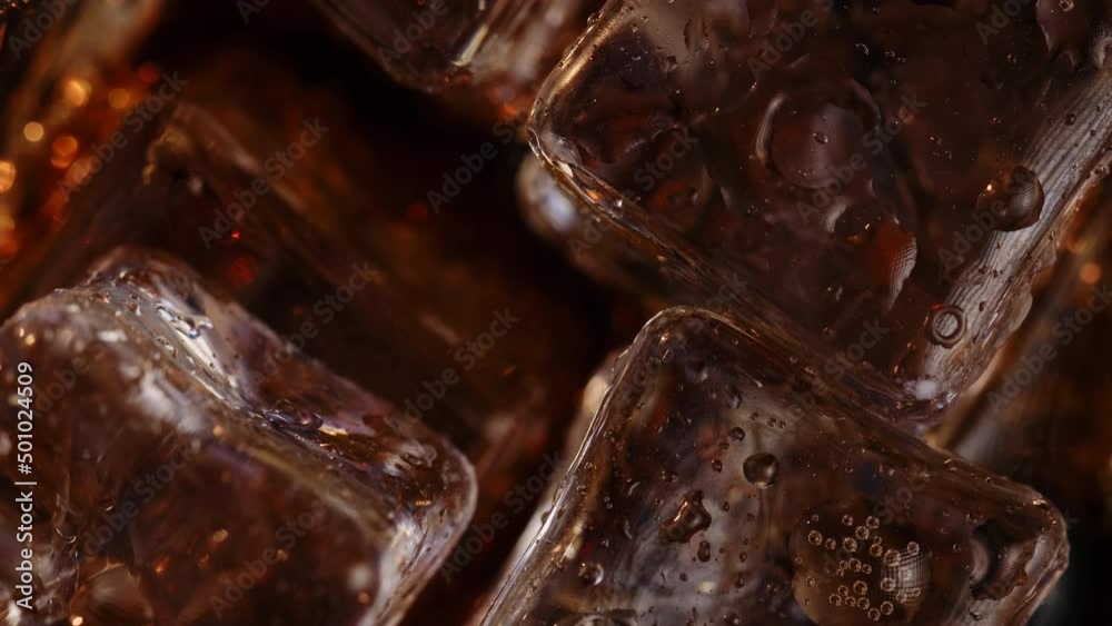 Close-up from above, ice cubes float in a carbonated drink and rotate Close-up from above, ice cubes float in a carbonated drink and rotate