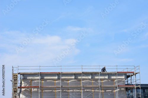 Construction worker on flat roof, scaffolded,blue sky