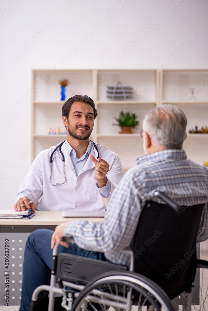 Old man in wheelchair visiting young male doctor Old man in wheelchair visiting young male doctor