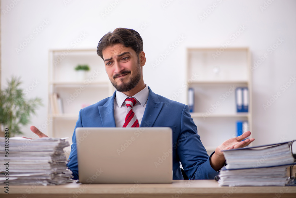 Young male employee and too much work in the office Young male employee and too much work in the office