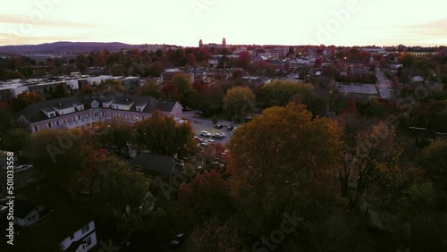 Aerial Shot Of Cars Parked In Parking Lot During Sunset, Drone Flying Backwards Over Autumn Trees - Fayetteville, Arkansas photo