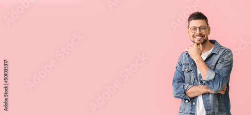 Handsome smiling man wearing glasses and jeans jacket on pink background with space for text