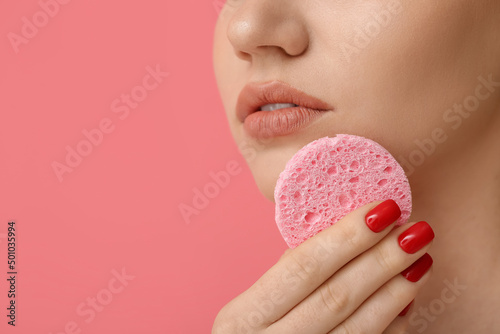 Beautiful woman with makeup sponge on color background, closeup photo