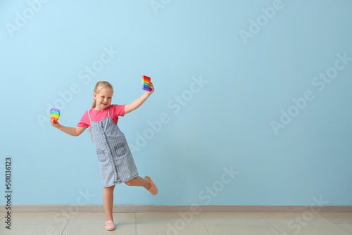 Happy girl with different pop it fidget toys near color wall