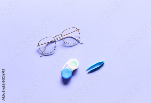 Stylish eyeglasses and contact lenses with container on purple background