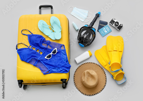 Beach accessories with suitcase, snorkeling mask and immune passport on light background photo