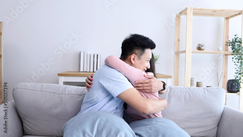Young Asian couple hugging on couch in living room at home, In love and romantic concept