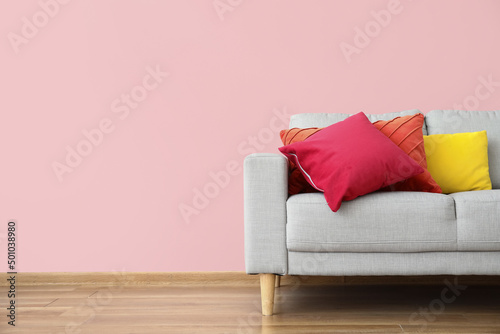 Modern sofa with pillows near color wall in room © Pixel-Shot