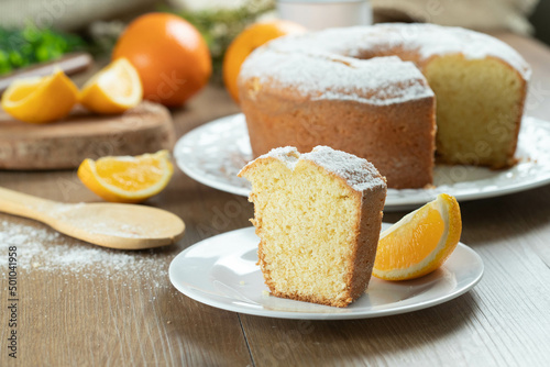 Close up piece of moist orange fruit cake on plate with orange slices on wooden table. Delicious breakfast, traditional English tea time. Orange cake recipe.