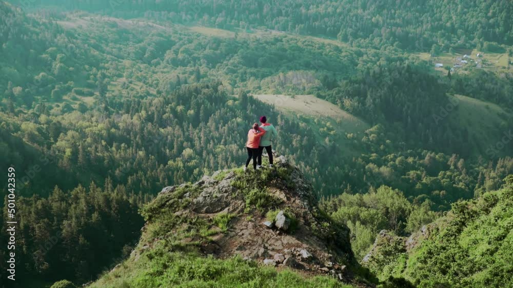 A young woman approaches a man to a cliff in a mountainous area. Travel A young woman approaches a man to a cliff in a mountainous area. Travel