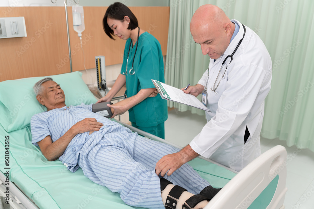 Doctor take care old patient leg with nurse pressure gauge in the room at hospital Doctor take care old patient leg with nurse pressure gauge in the room at hospital