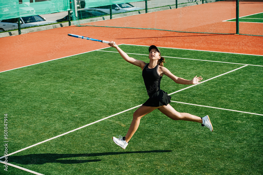 Fototapeta premium Running girl playing on overhead ball on a brand new outdoor tennis court