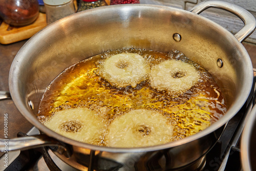 Cooking apple pancake. Apple donut in boiling oil