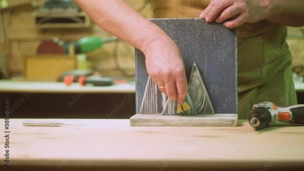 A mature carpenter makes works in his carpentry workshop, glues together wooden blanks