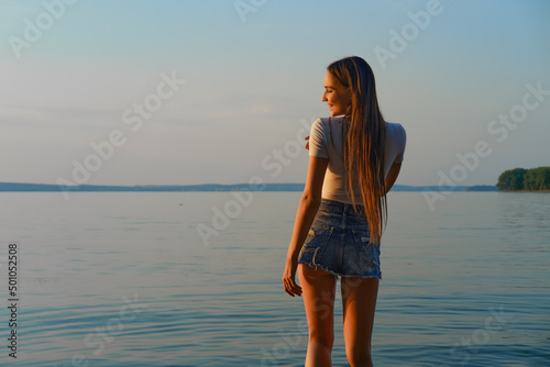 Cute woman stands by the water in a recreation area