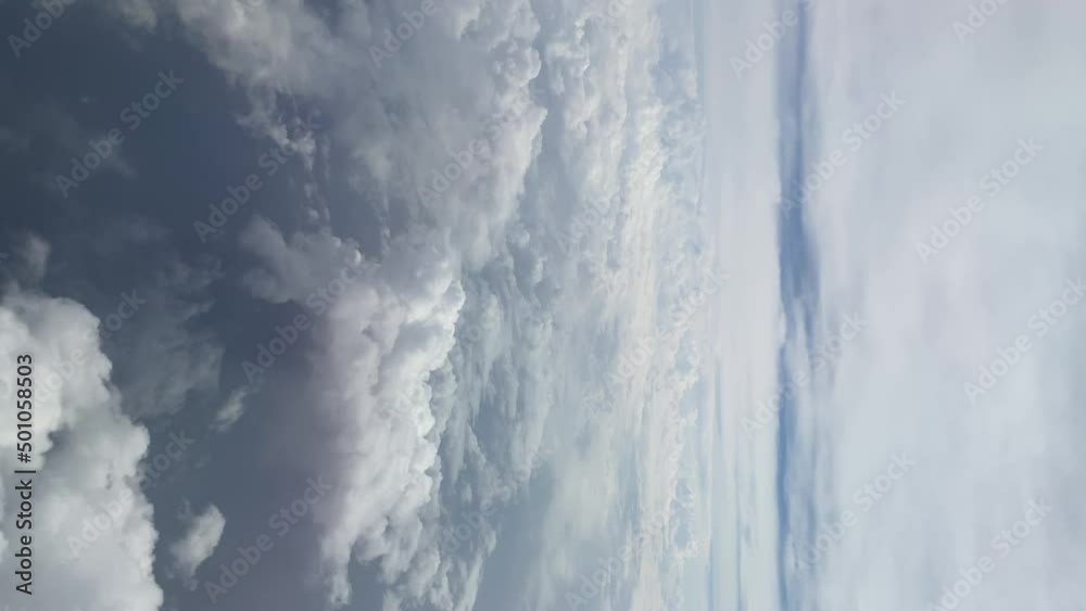 Cloudscape visible through window of airplane flying mid air. Vertical view. Cloudscape visible through window of airplane flying mid air. Vertical view.