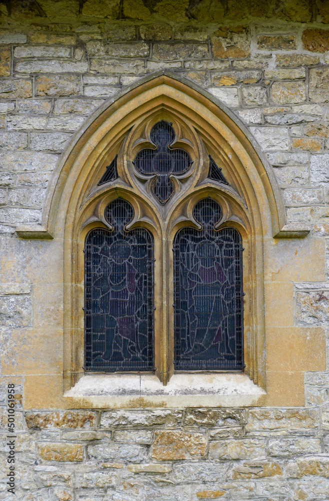 Arched window of old stone church in England UK. Details of village church window, vertical image.