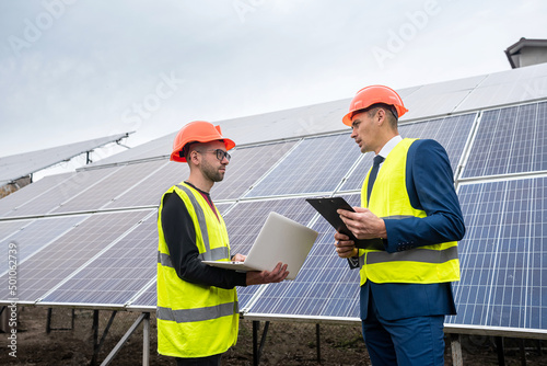 handsome young guys in hard hats with documents stand near the newly installed panels.