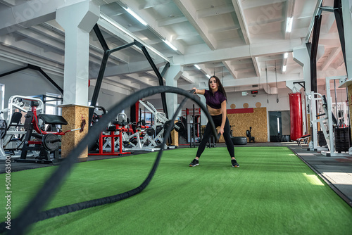 Fotografie Young female trainer exercise training with rope in gym