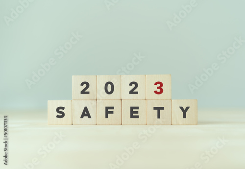 Work safety in 2023. Safety first, caution work hazards, danger surveillance, zero accident concept. Work safety planning and compliance. Wooden cubes inscripted 2023 and safety on smart background. photo
