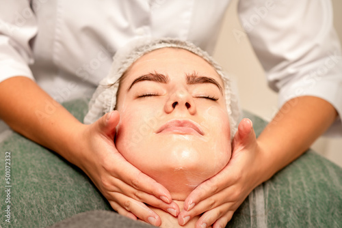 Face massage. Beautiful caucasian young white woman having a facial massage with closed eyes in a spa salon