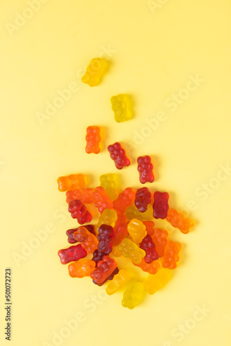 Colored jelly bears on an yellow background. Top view