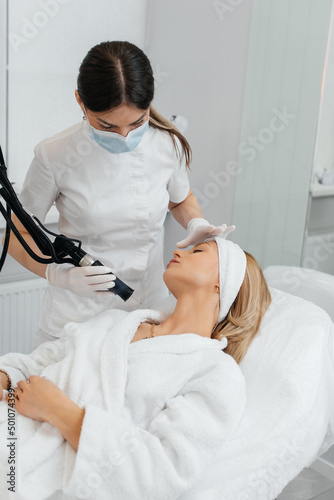 A young girl gets a carbon peeling for the skin of the neck in a beauty salon. Laser pulses cleanse the skin. Hardware cosmetology. The process of photothermolysis  warming the skin.
