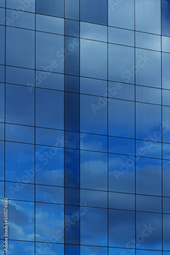glass facade with blue sky and clouds reflected on it