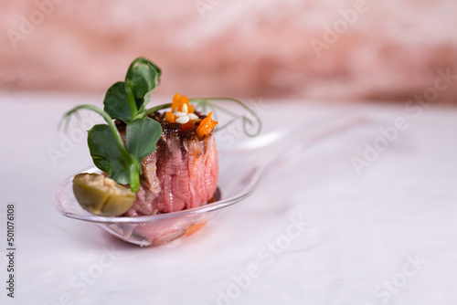 Sandwich with meat and capers on a plastic spoon