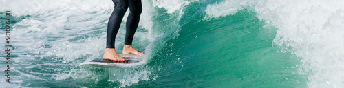 Wakeboarding. Close up of woman in wetsuit learning to wakesurfing behind wakeboard boat. Female surfing motorboat waves on river. Banner image with copy space