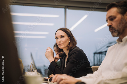 Confident mature businesswoman discussing with colleagues in office photo