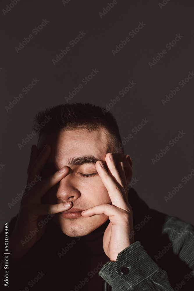 Young man with eyes closed touching face against wall Young man with eyes closed touching face against wall