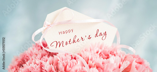 Banner with Happy Mother's Day tag in bouquet of pink carnations. © Olga Zarytska